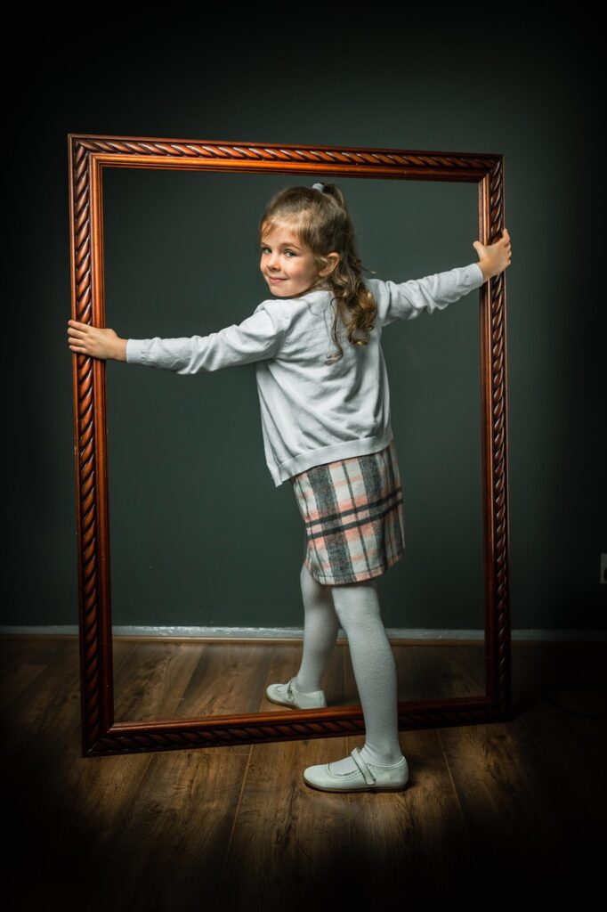 A young girl holds the molding part of a picture frame