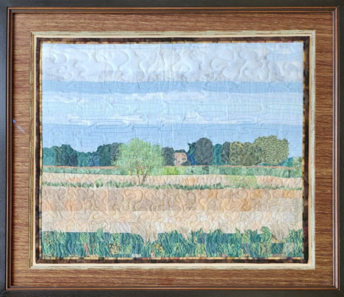 Image of a field ripe for sowing on a quilt in a picture frame.